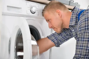 Technician inspecting the drum of a front-loading washing machine.
