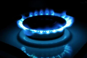 Close-up of a clean, steady blue flame on a gas cooktop burner, signifying proper function.